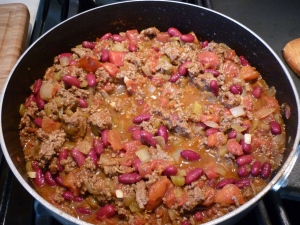 Fry ground beef, onion, and garlic together in oven-proof skillet. Stir in tomatoes, chiles, beans, and taco seasoning. Let simmer for a few minutes. 